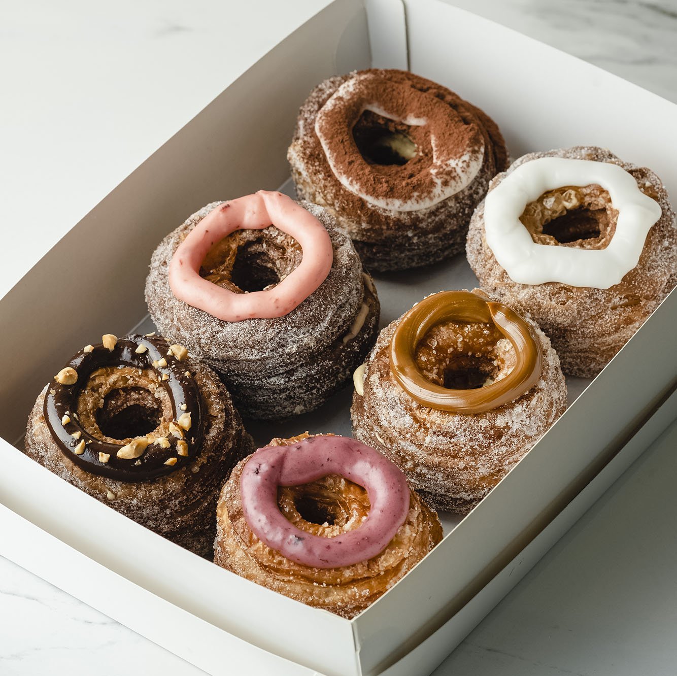 6 piece box of assorted cronut dessert pastry topped with dulce de leche, tiramisu, vanilla, strawberry, hazelnut,
